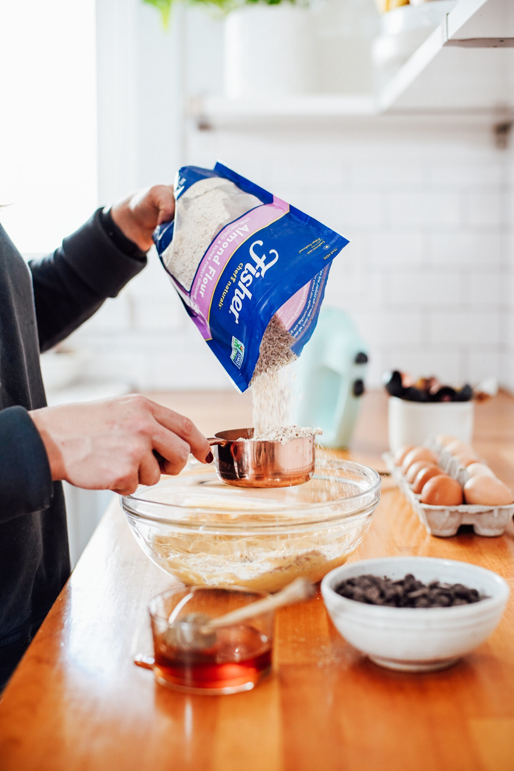 Pouring almond flour from a bag into a measuring cup.