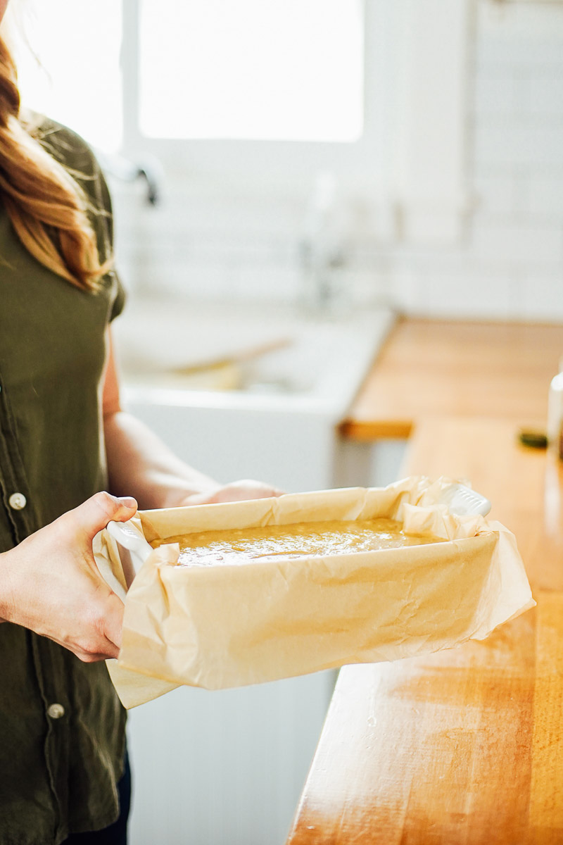 Banana bread batter in a white ceramic bread pan lined with parchment paper.