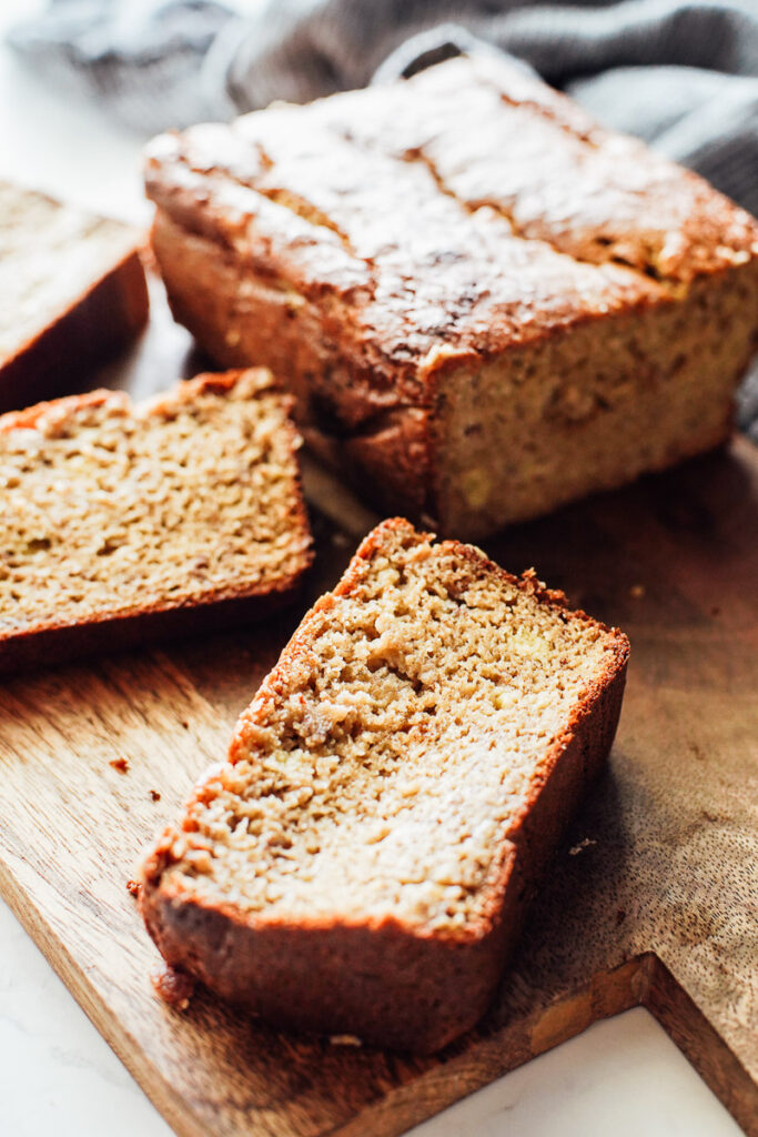 Sliced almond flour banana bread on a wood cutting board.