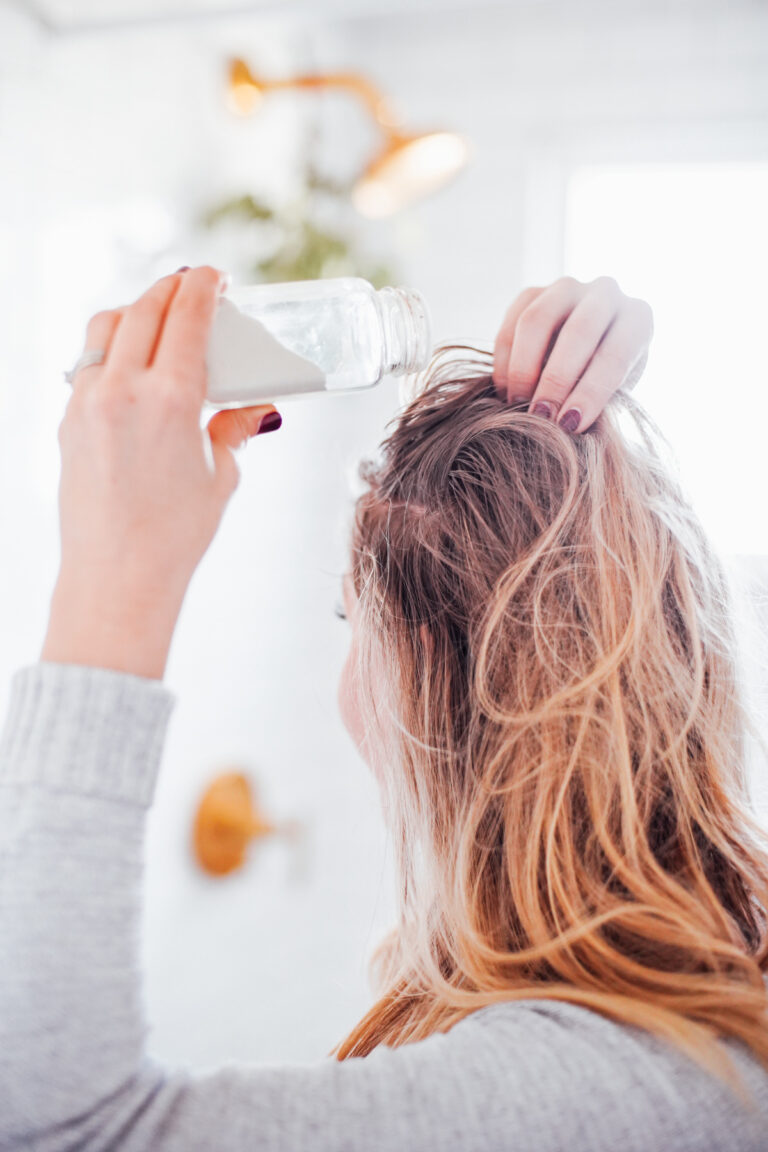 Sprinkling dry shampoo on hair.