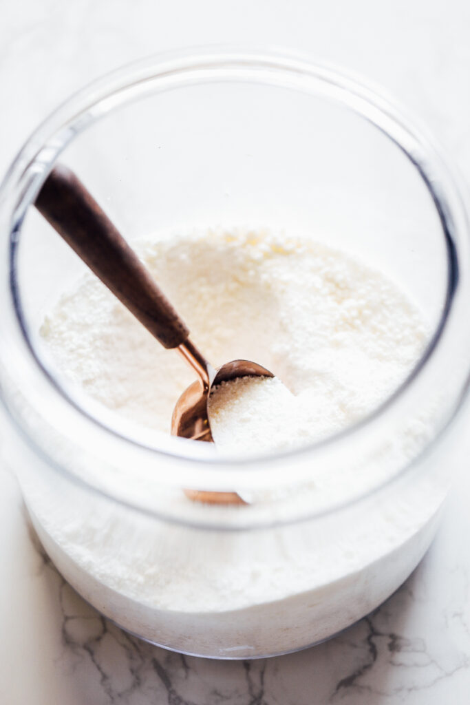 Laundry soap powder in a glass jar with a scoop.