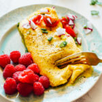 Egg Cheese Omelette on a turquoise plate, cutting into the omelette with a gold fork.