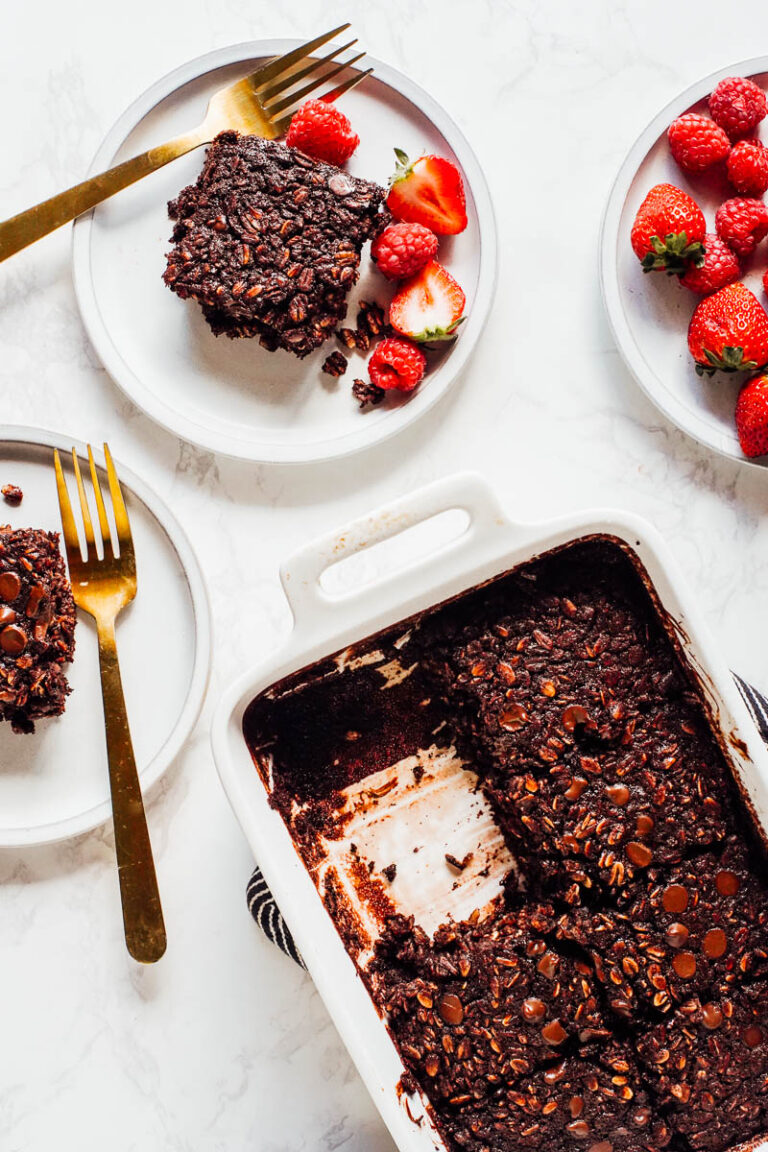 Slices of baked oatmeal removed from the pan and on two plates with berries.