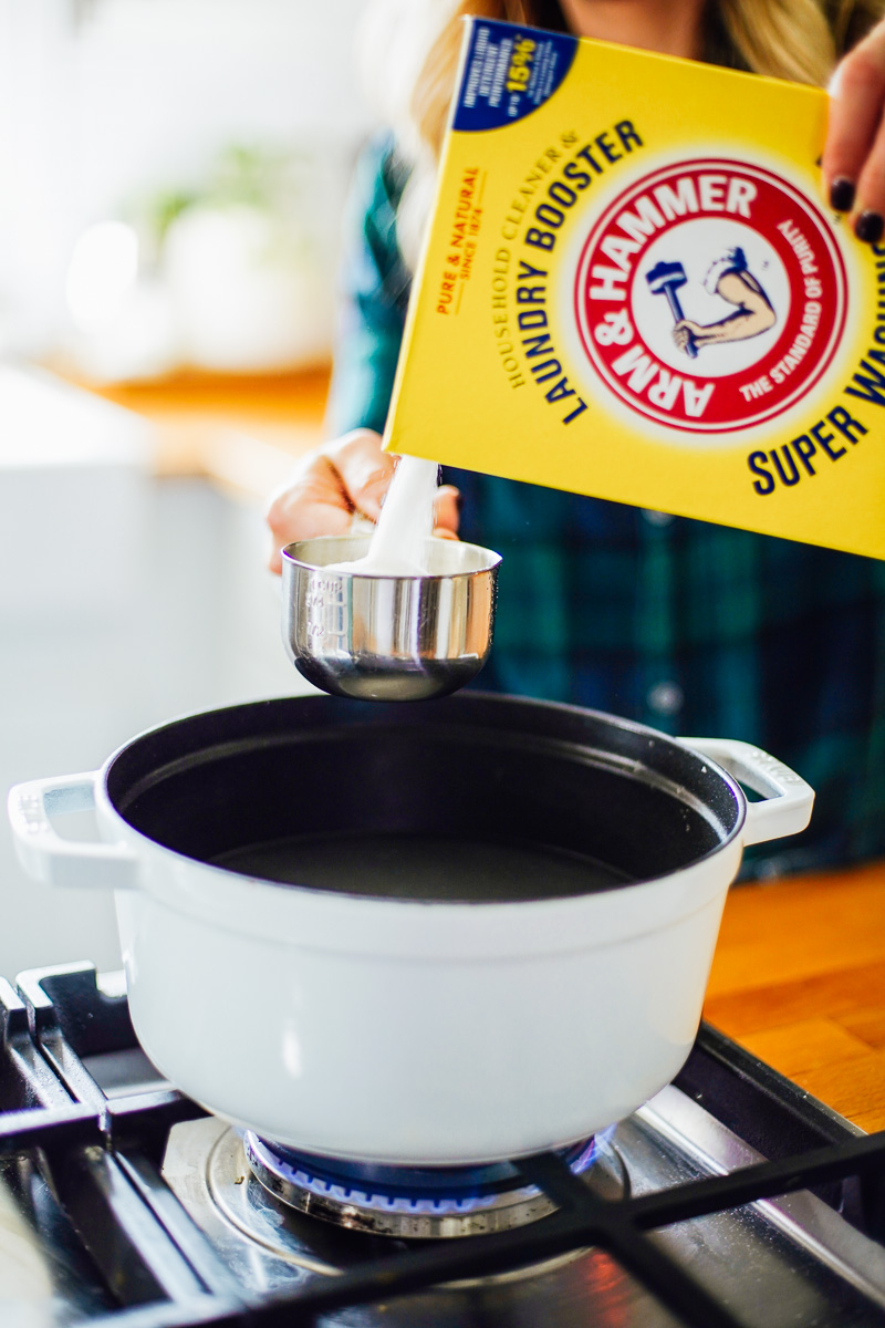 Pouring washing soda into the dutch oven.