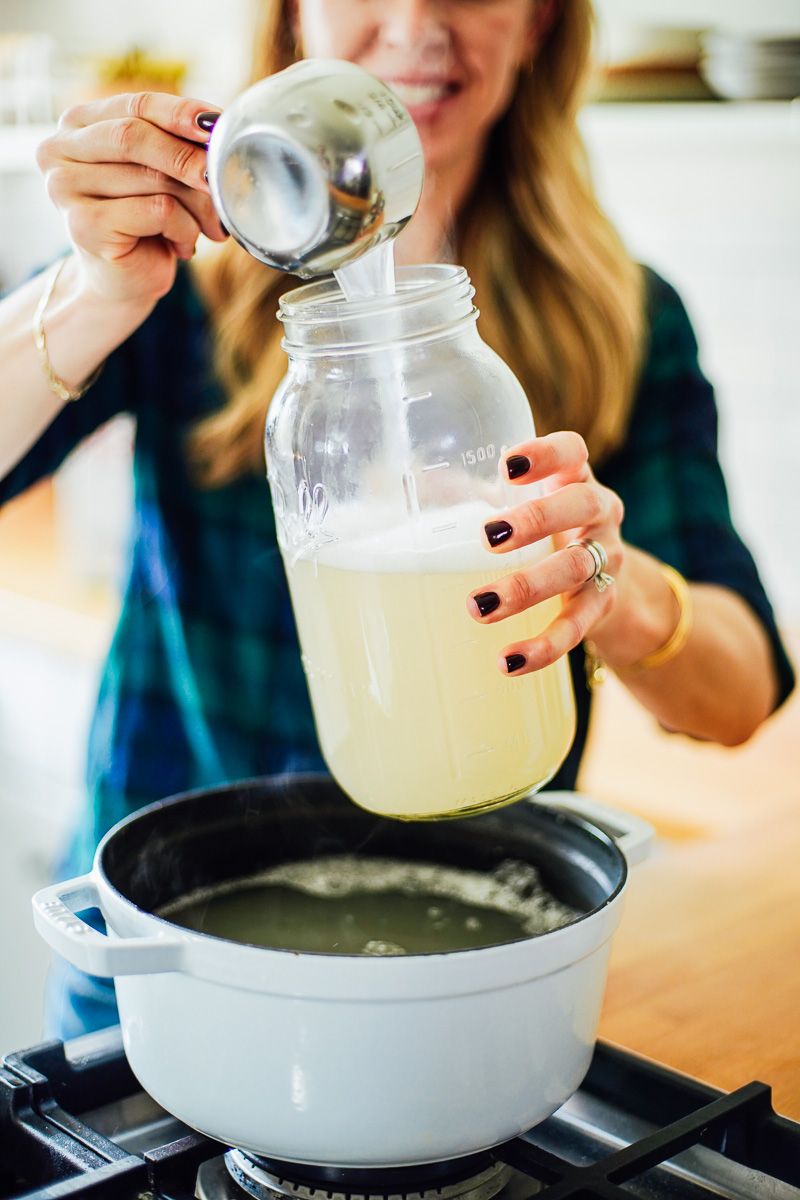 Pouring the laundry soap into a large glass mason jar.