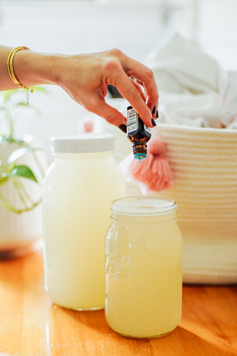 Adding essential oil to the detergent in a glass jar.