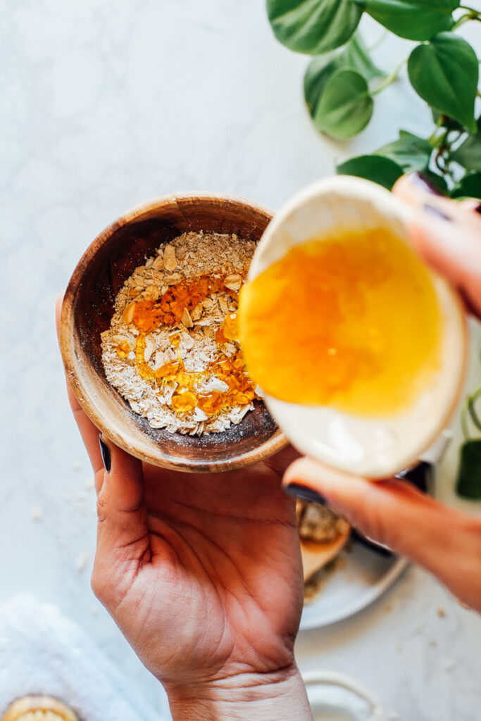 Adding honey to oats in a bowl. 