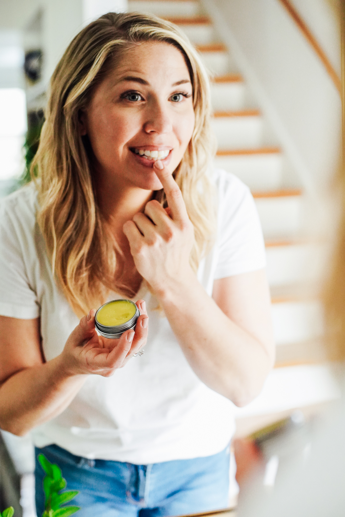 Applying lip balm from a metal tin to lips.