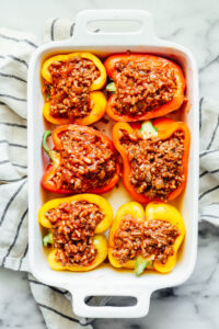 Ground beef and rice filling stuffed in bell peppers in a baking dish.