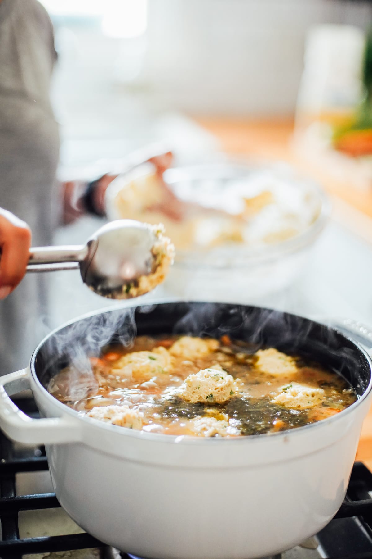 Adding dumpling mixture to soup pot