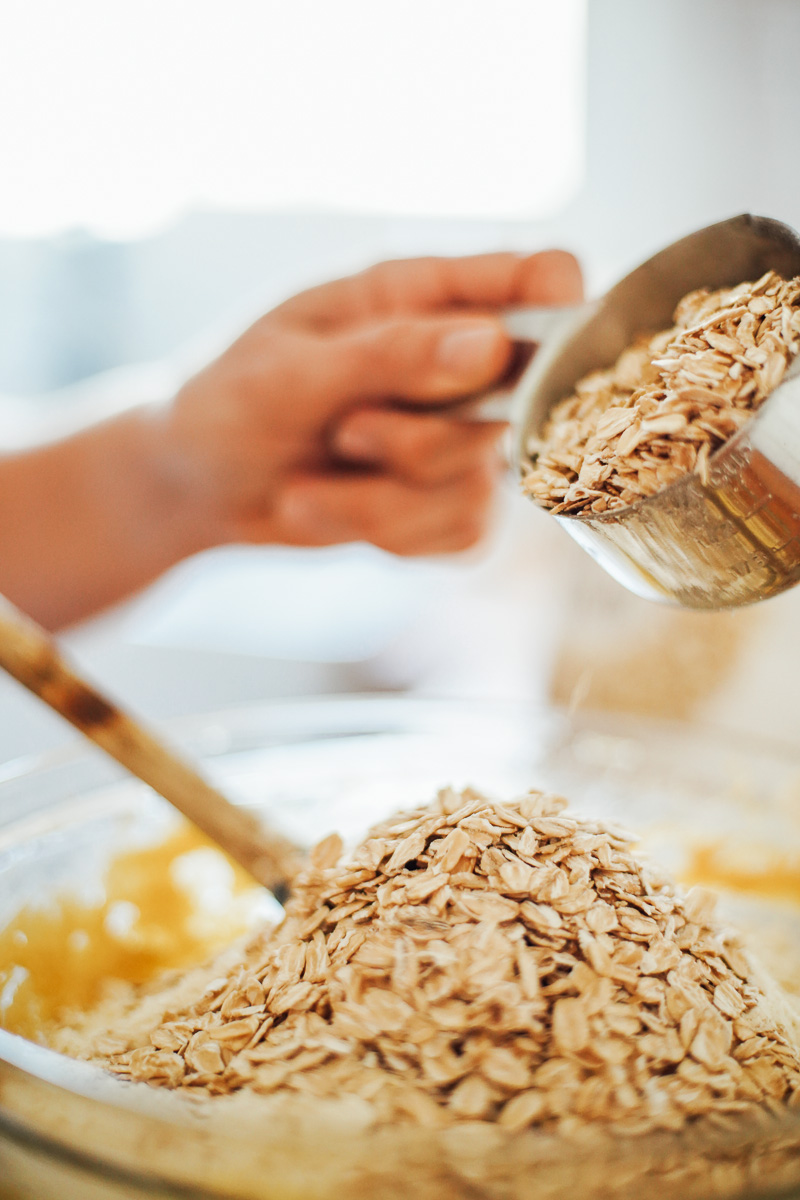 Adding rolled oats to the cookie dough.