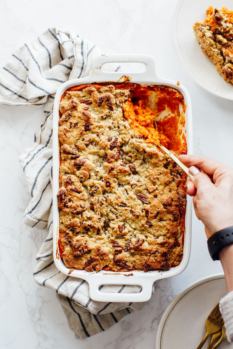 Scooping sweet potato casserole from a casserole dish.