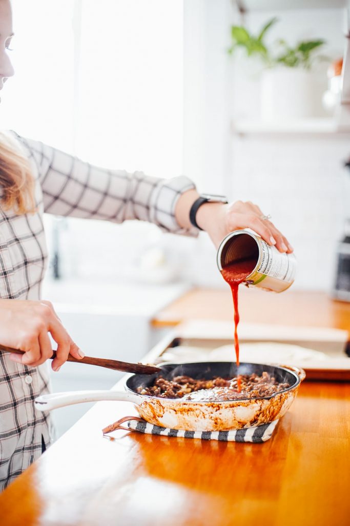 Pouring tomato sauce into ground beef mixture