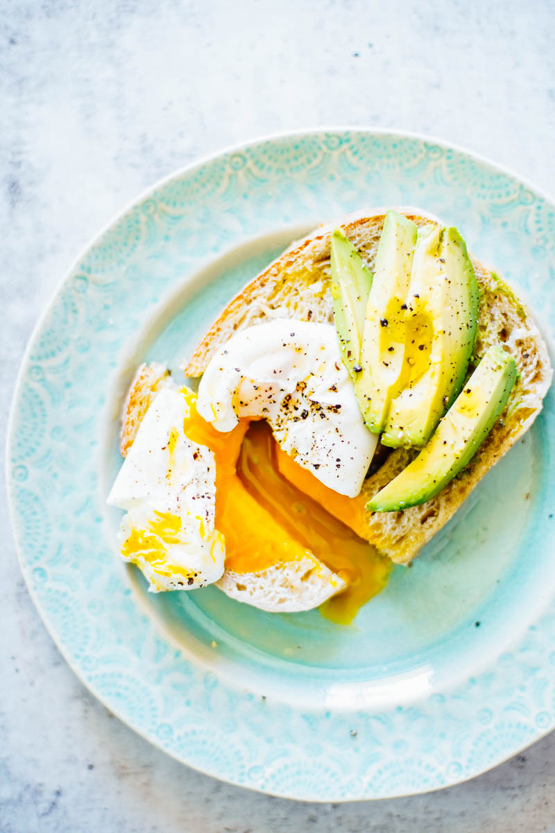 Toast topped with avocado slices and a runny sunny side up egg.