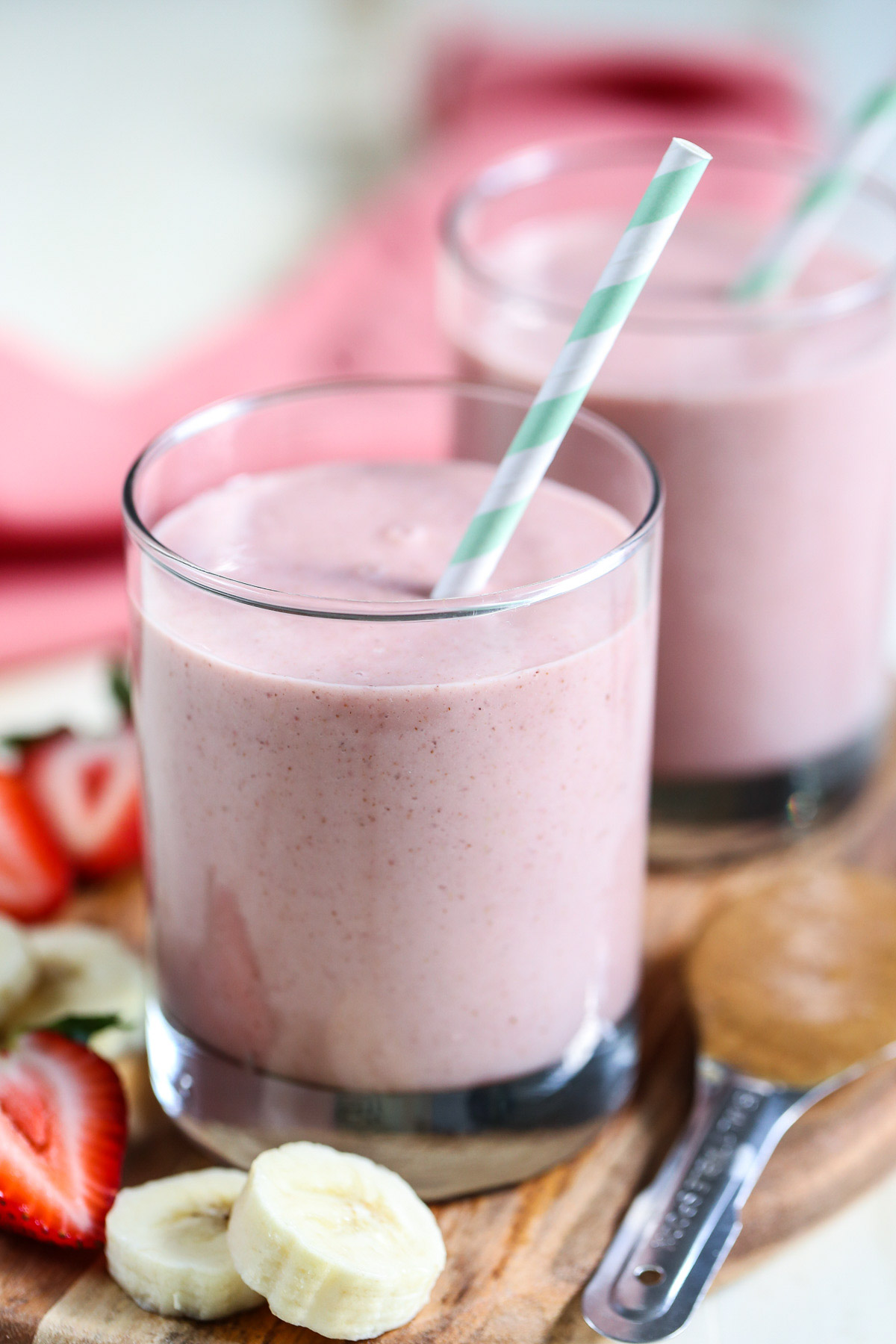 Peanut Butter and Jelly Smoothie in small drinking glasses with blue stripped straws.