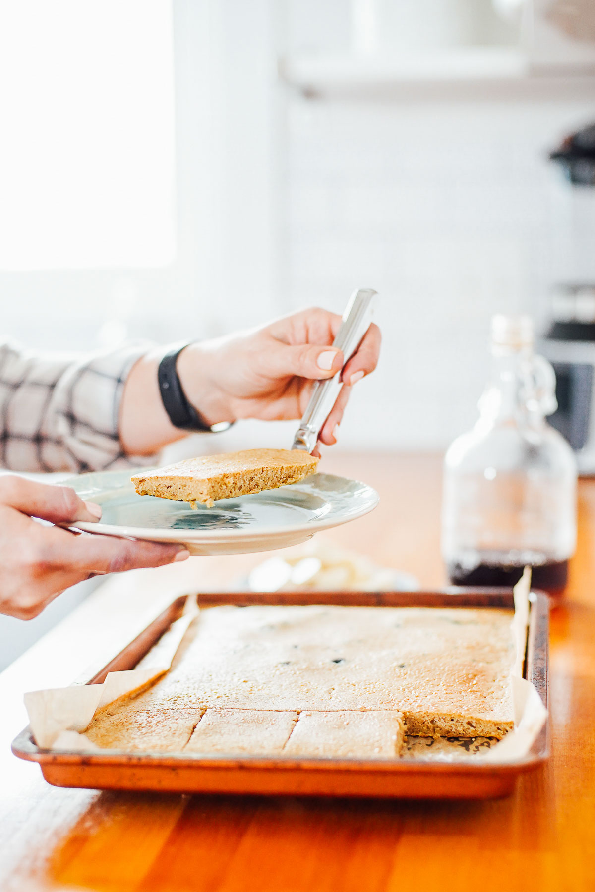 Pancakes baked on a sheet pan, cutting a slice and lifting onto a plate.