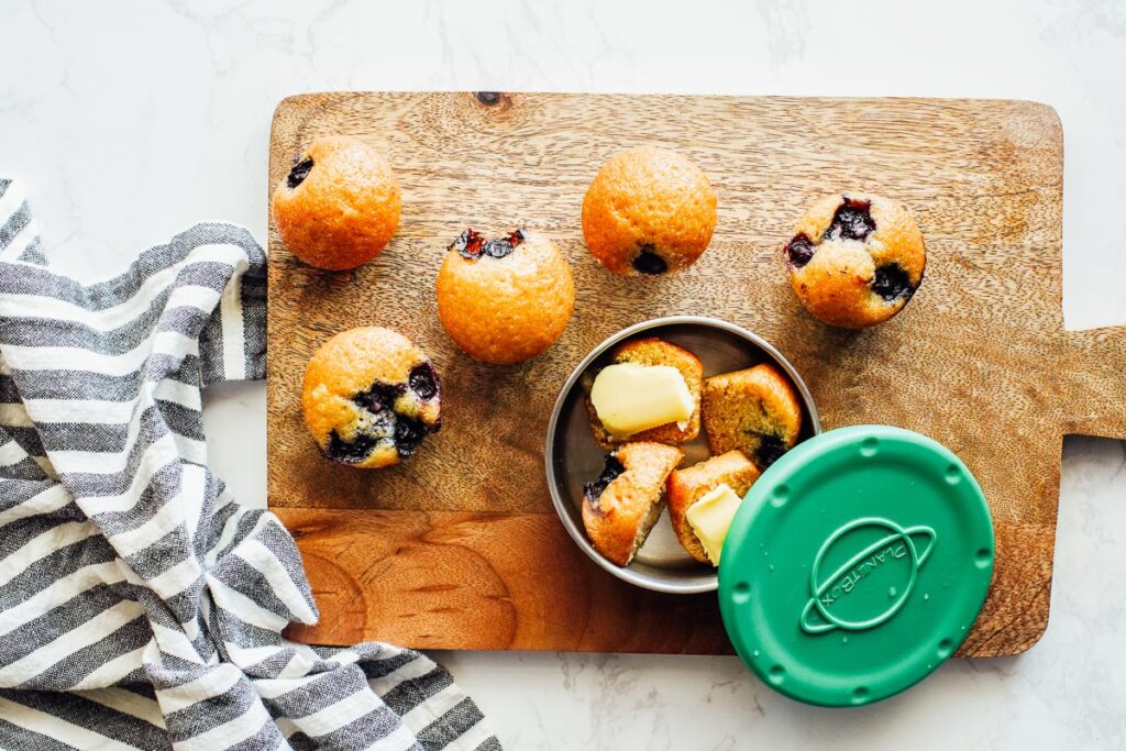 Blueberry muffins on a cutting board and container.