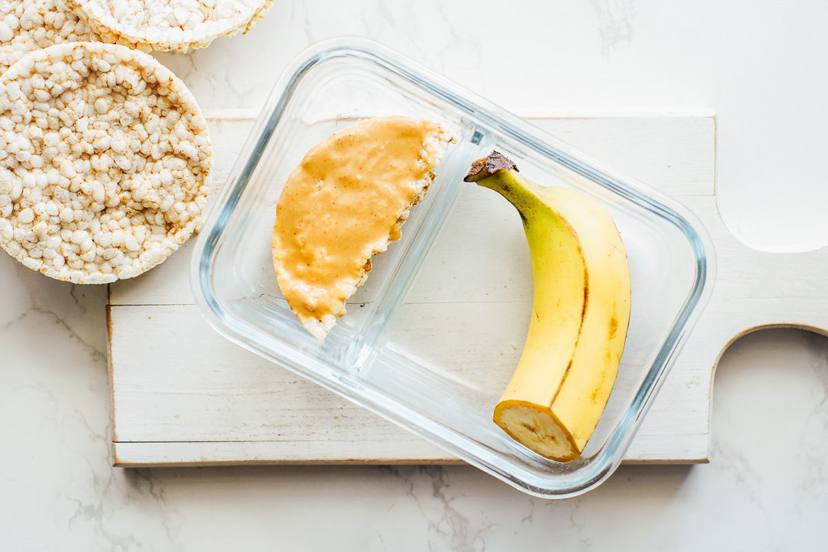 Rice cake spread with peanut butter and banana on the side. 