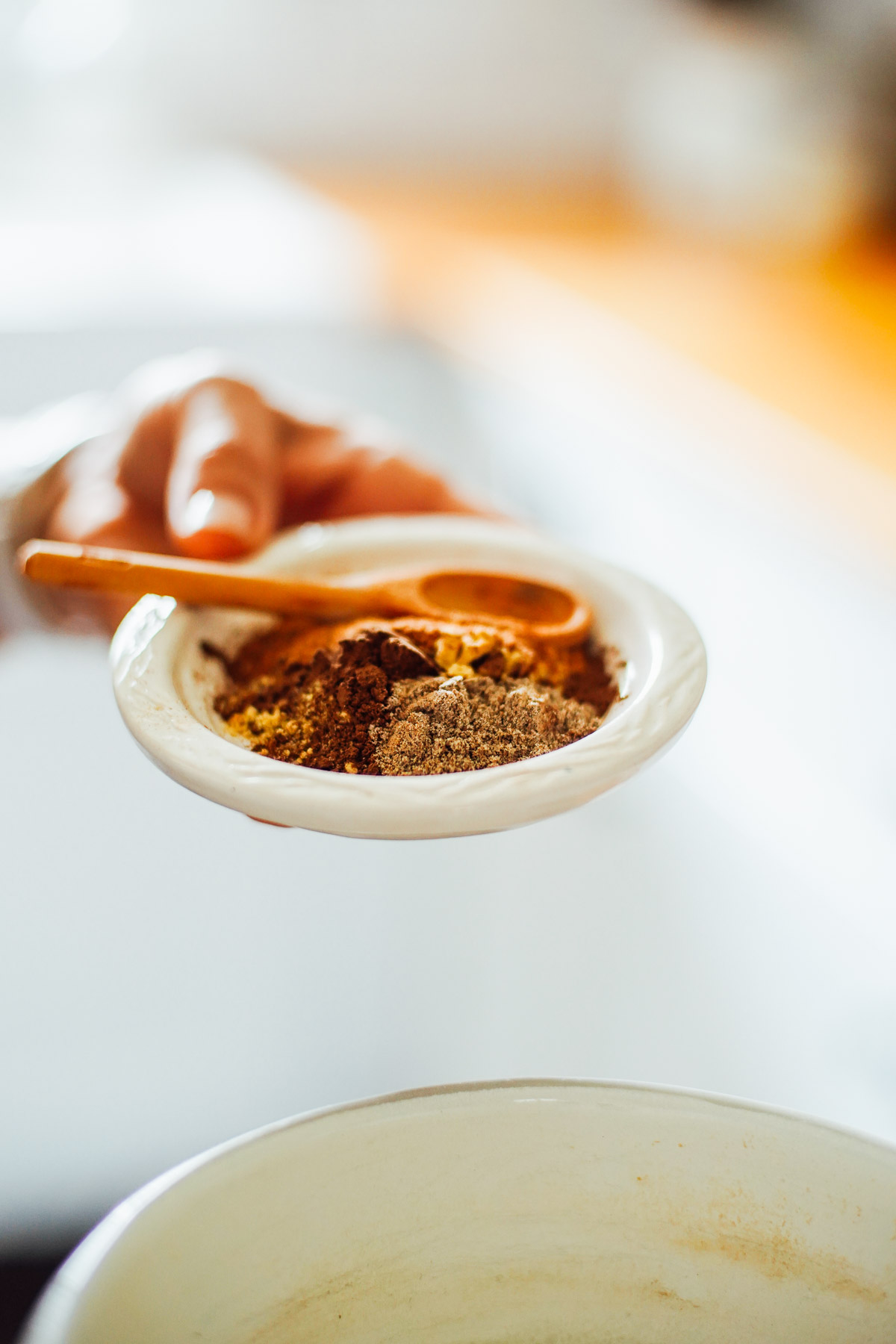 Spices used to make a chai latte in a ceramic white bowl.