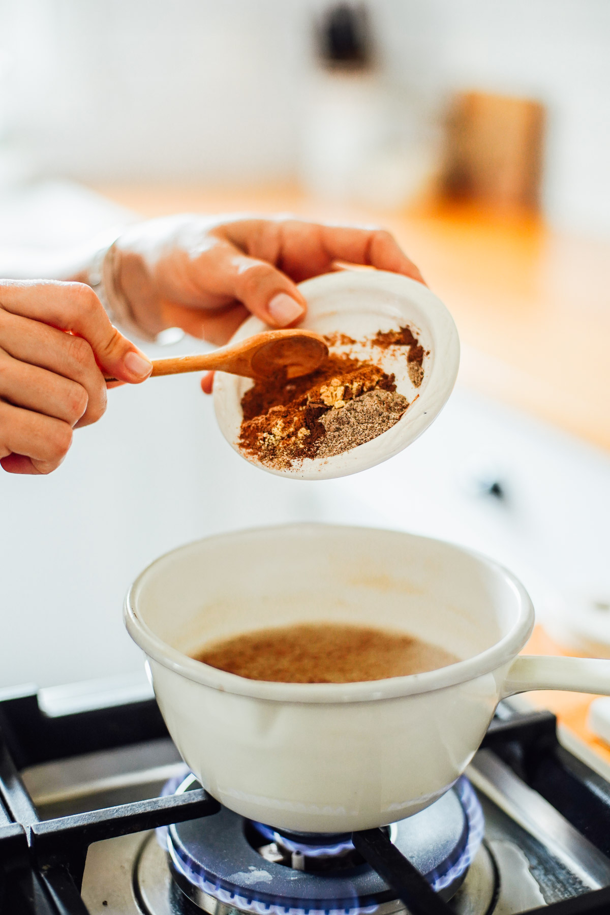 Adding spices to a pot of boiling water on the stove-top.