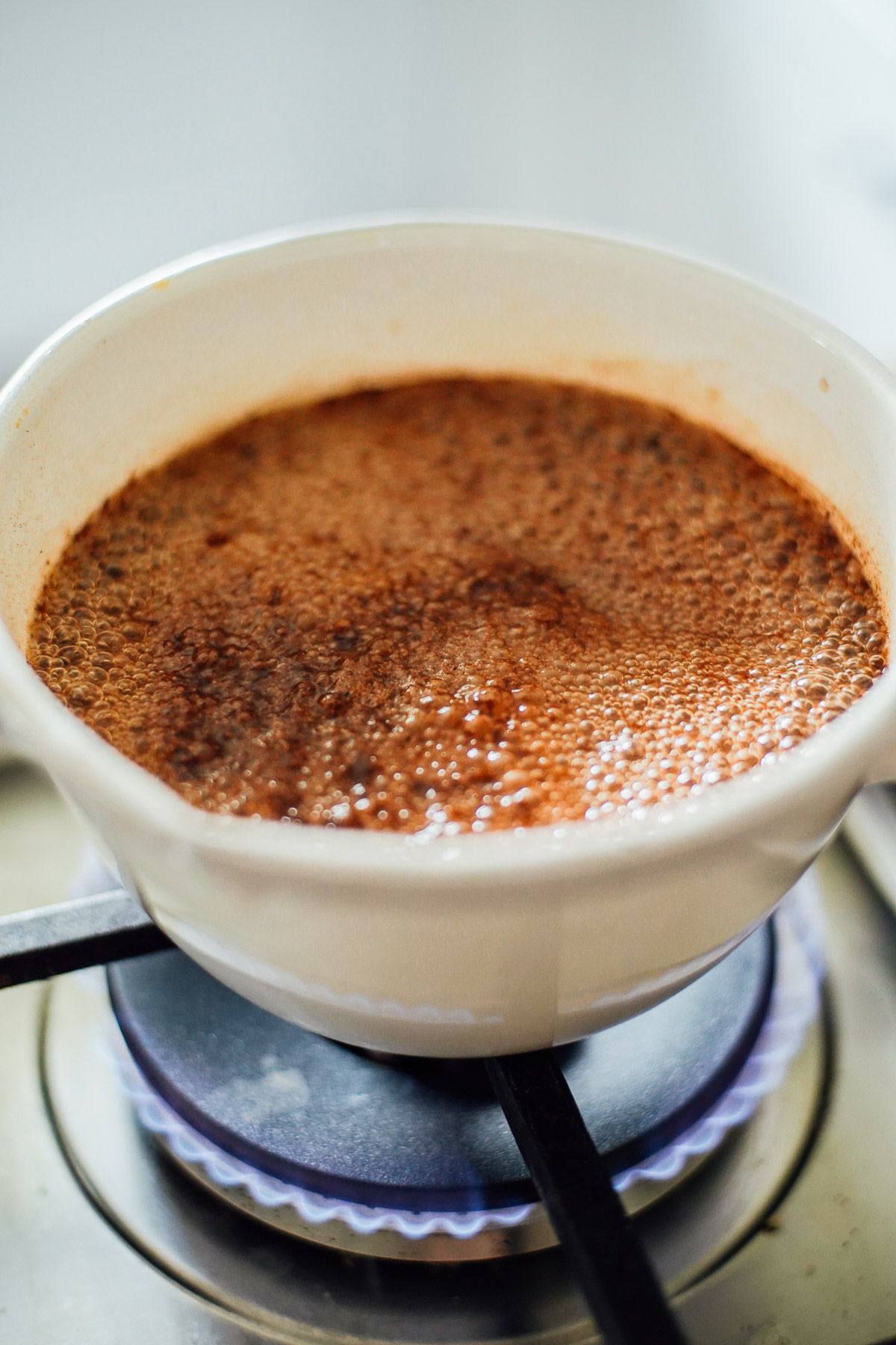 Spices boiling in a white pot on the stove-top.