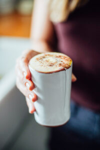 Hand holding a ceramic mug filled with chai latte.