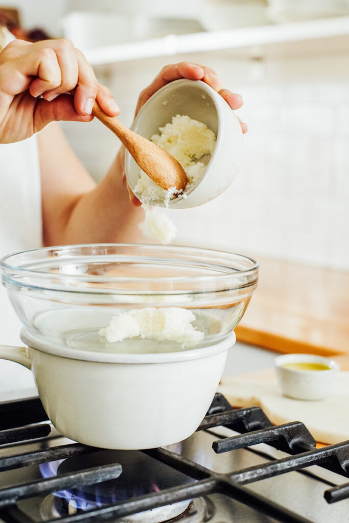 Placing the shea butter in a double boiler to melt. 