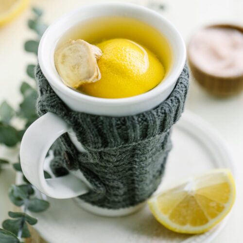 Tea in a white mug with fresh lemon and ginger.