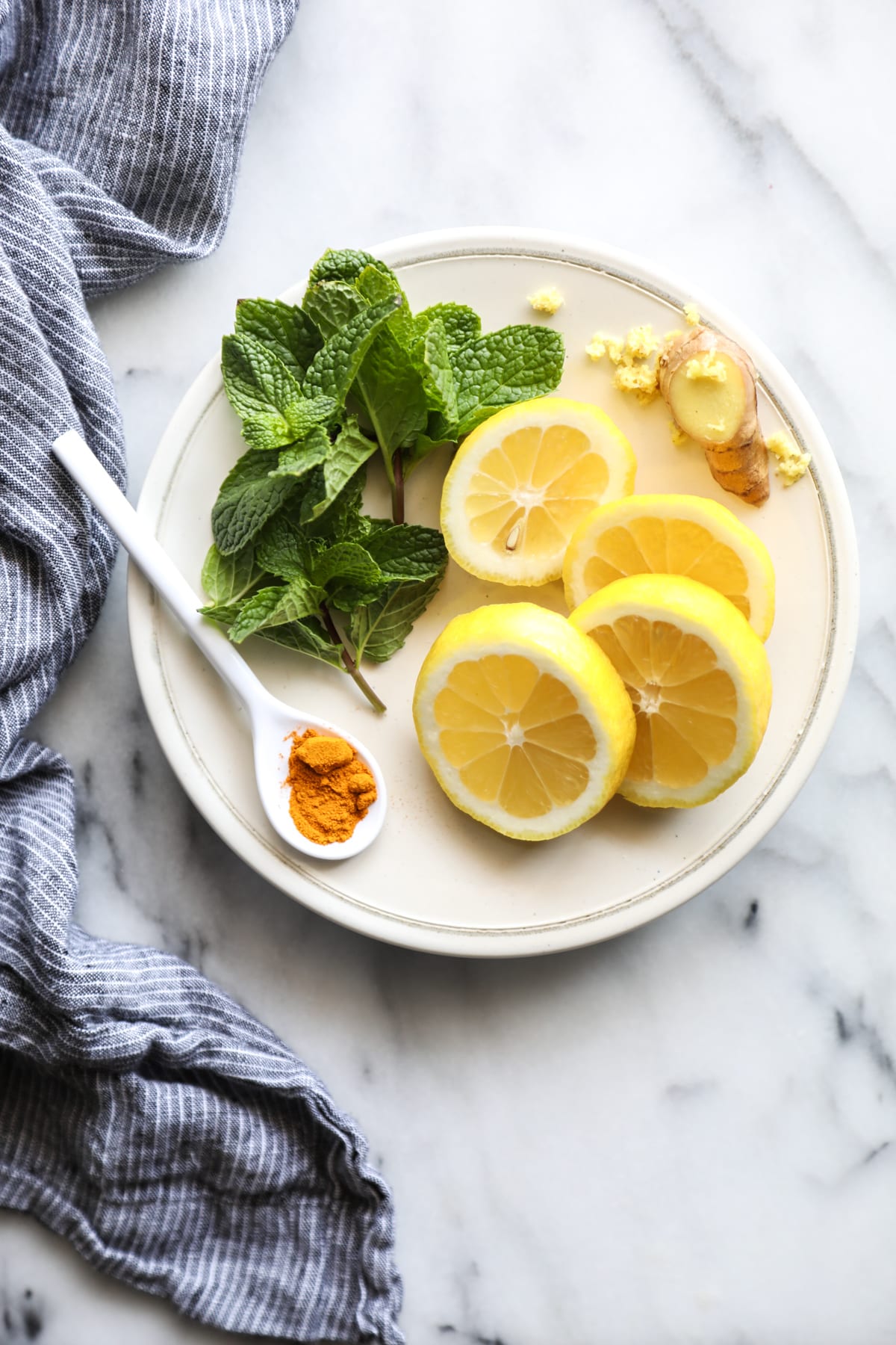 Different variation ingredients on a plate: fresh mint and powdered turmeric. 