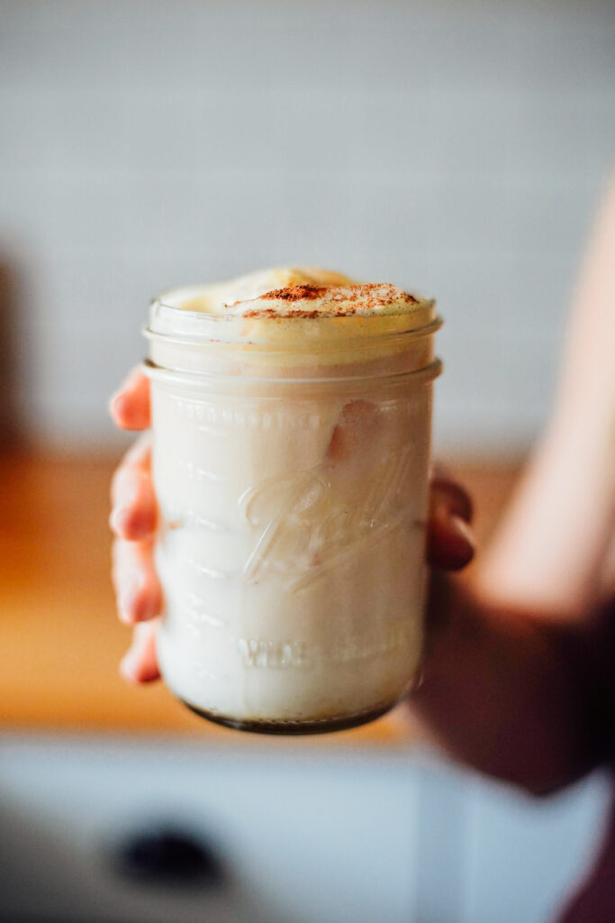 Hand holding a chai latte in a mason jar.