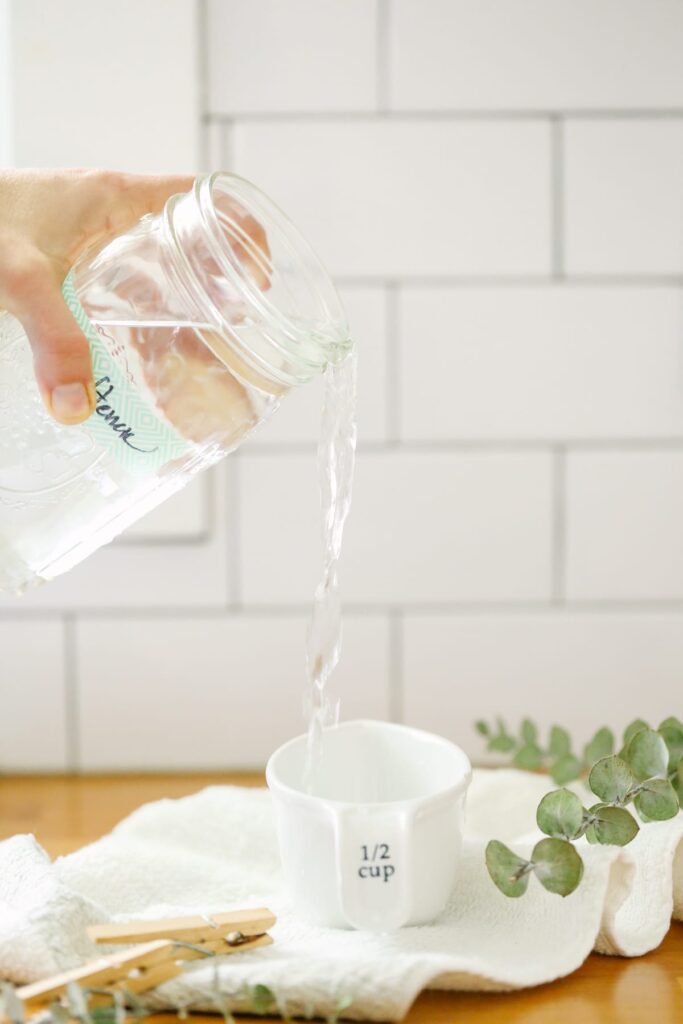 Pouring vinegar into a measuring cup before adding to the laundry. 