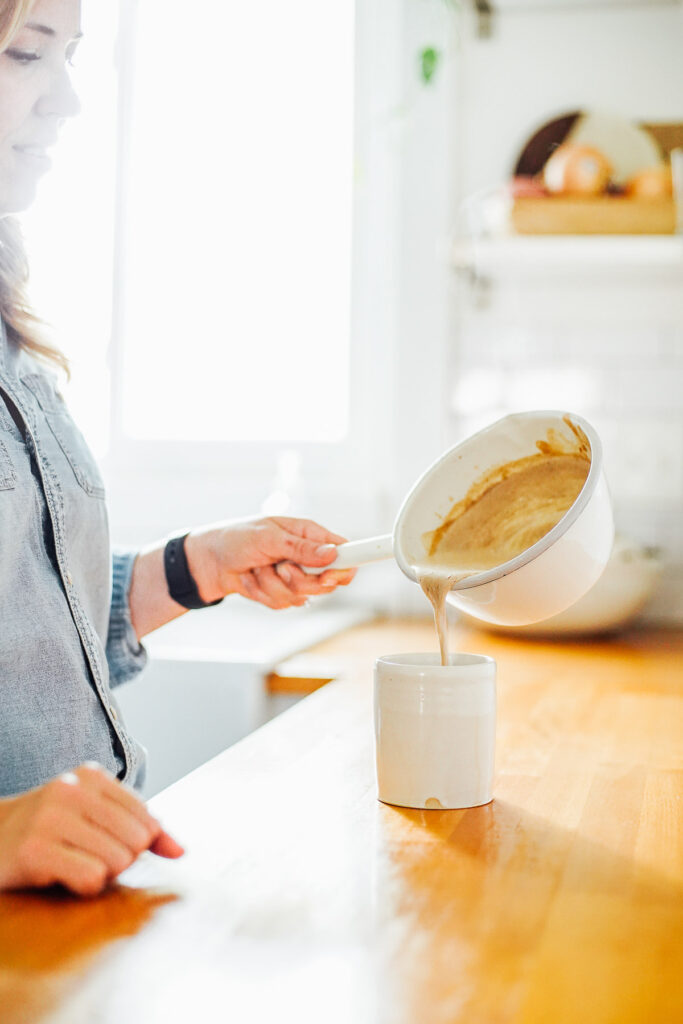 Pouring the hot pumpkin milk into the coffee cup with coffee inside.