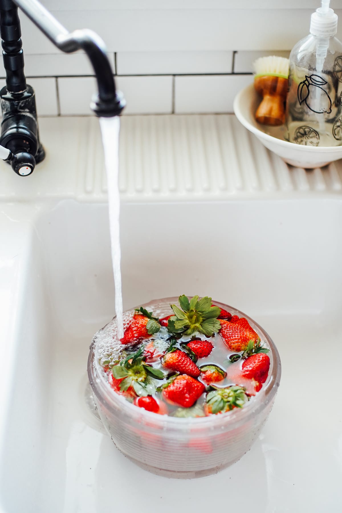 Strawberries in a salad spinner, filling with water.