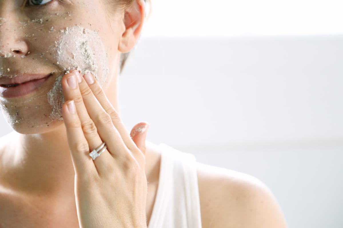 Spreading a clay mask on face with fingers. 