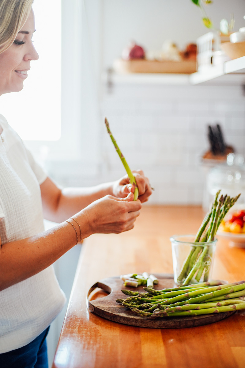 Placing the asparagus upright in a glass jar.