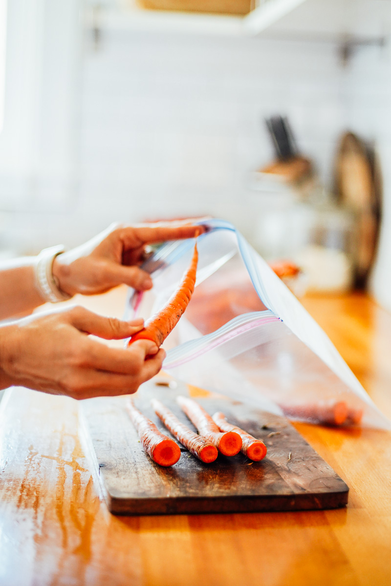 Placing whole unpeeled carrots in a storage bag. 