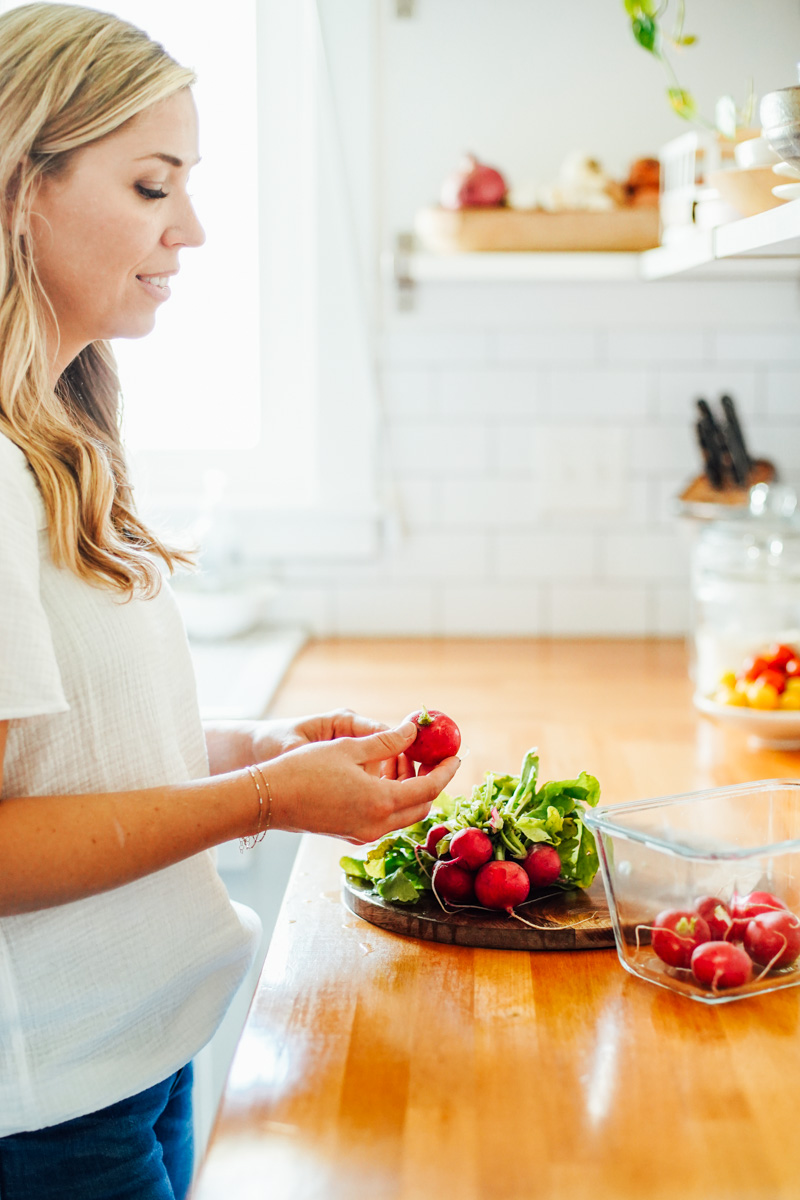 Radishes on the counter, being picked up a woman.