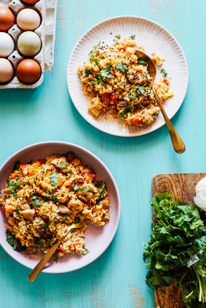 Fried rice on pink plates on a turquoise table.