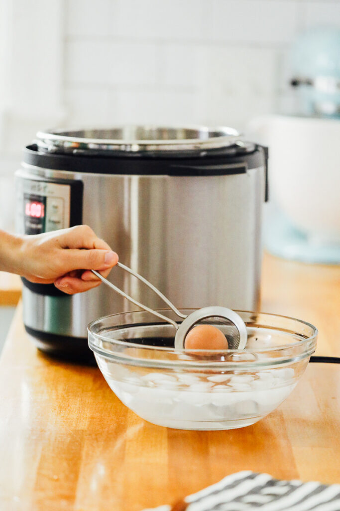 Adding the hardboiled eggs to an ice water bath. 