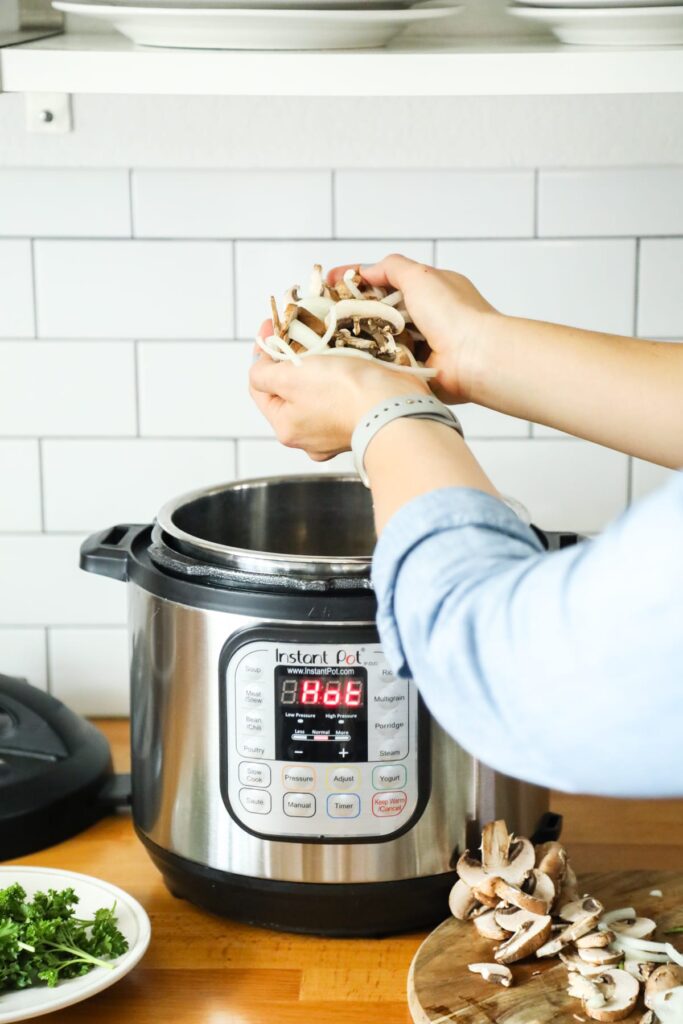 Adding mushrooms and onions to the Instant Pot.