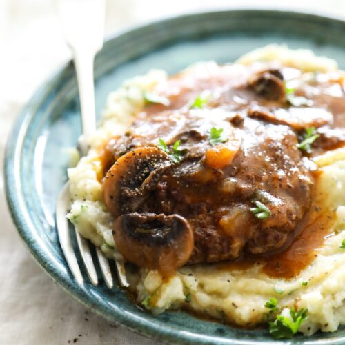 Salisbury steak on a plate with mashed potatoes