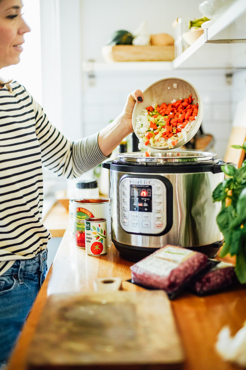 Pouring the chopped veggies from a bowl into the hot Instant Pot.