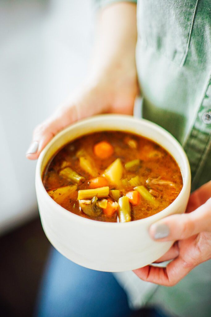 Hands holding a bowl of hot Instant Pot Vegetable Beef Soup