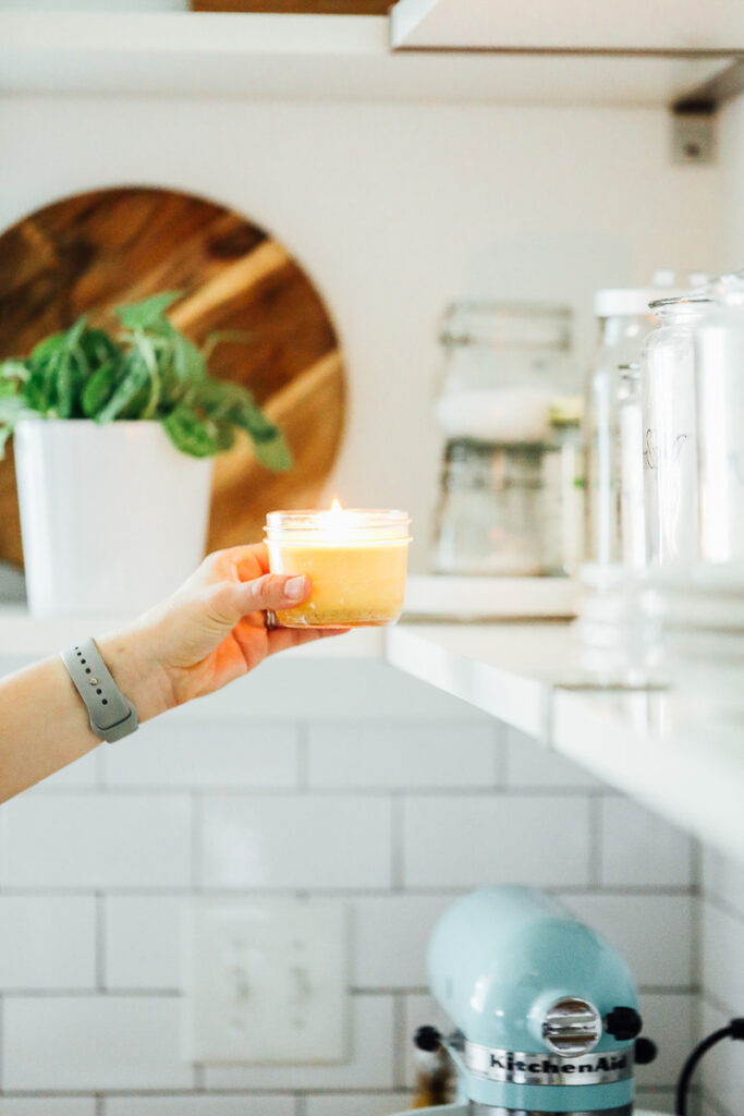 Holding a beeswax candles, lit with a flame.