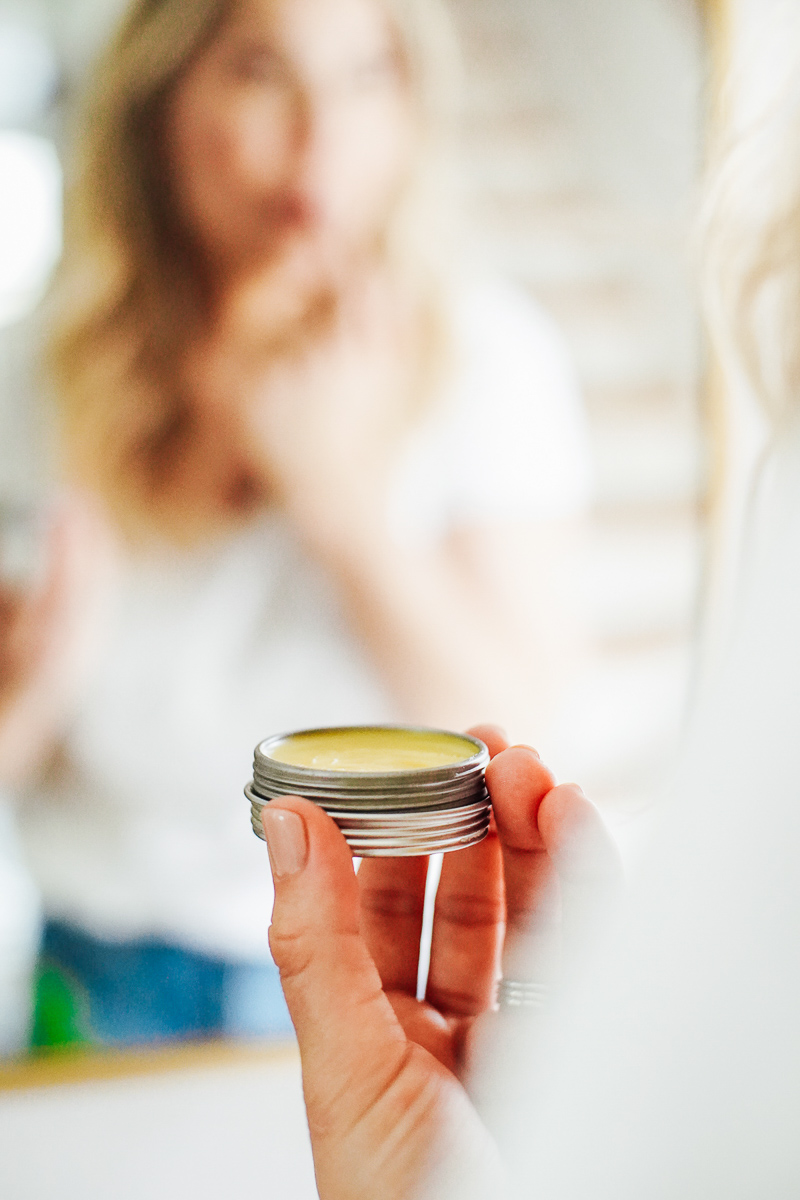 Holding a metal tin with lip balm inside.