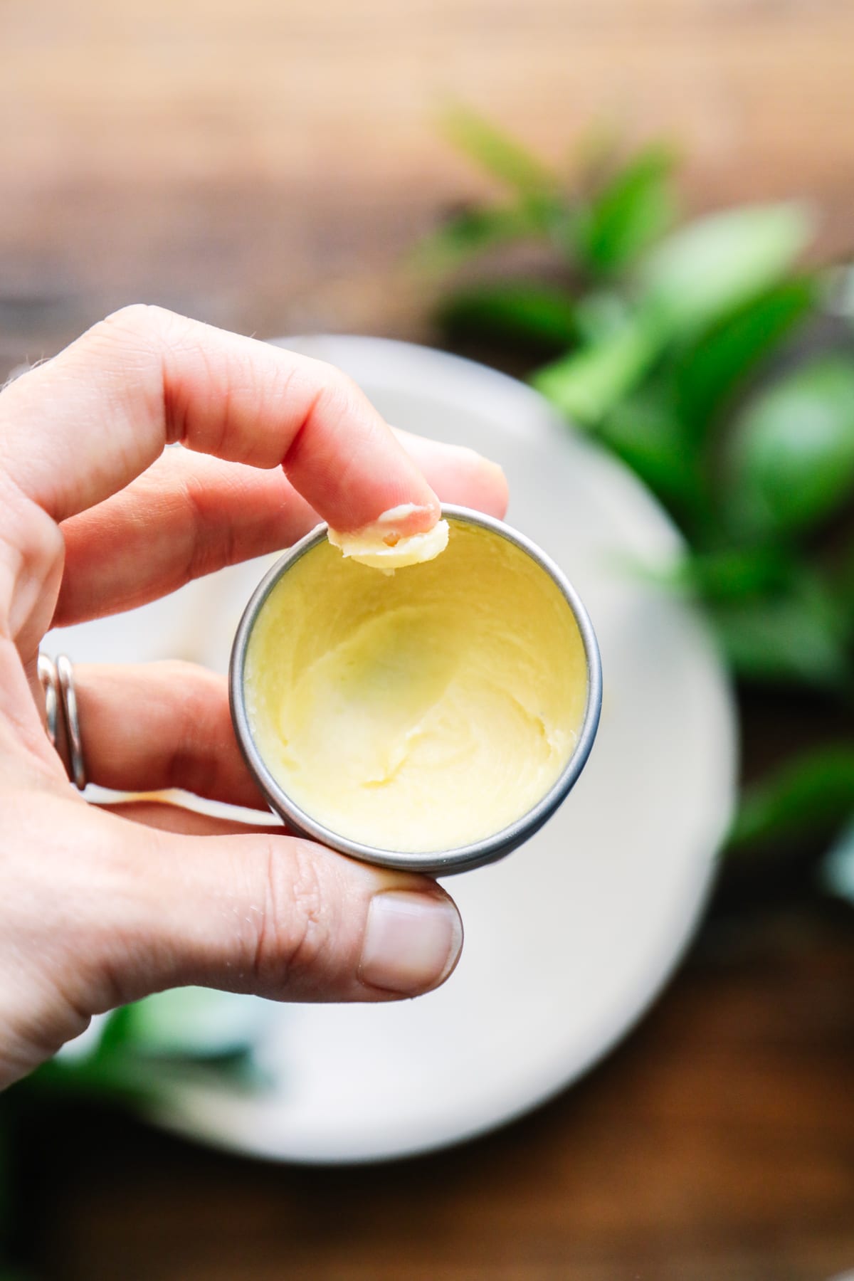 Scooping lip balm from a metal tin. 