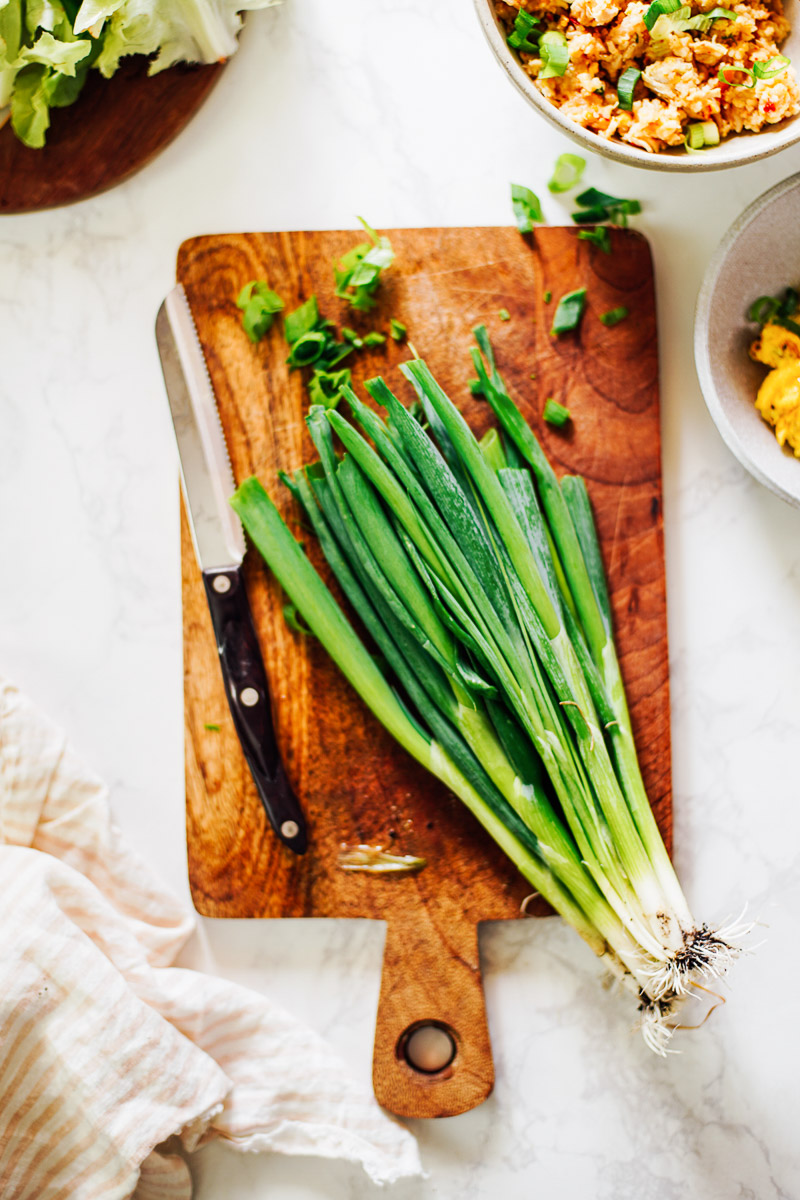 Cut green onions on a cutting board. 