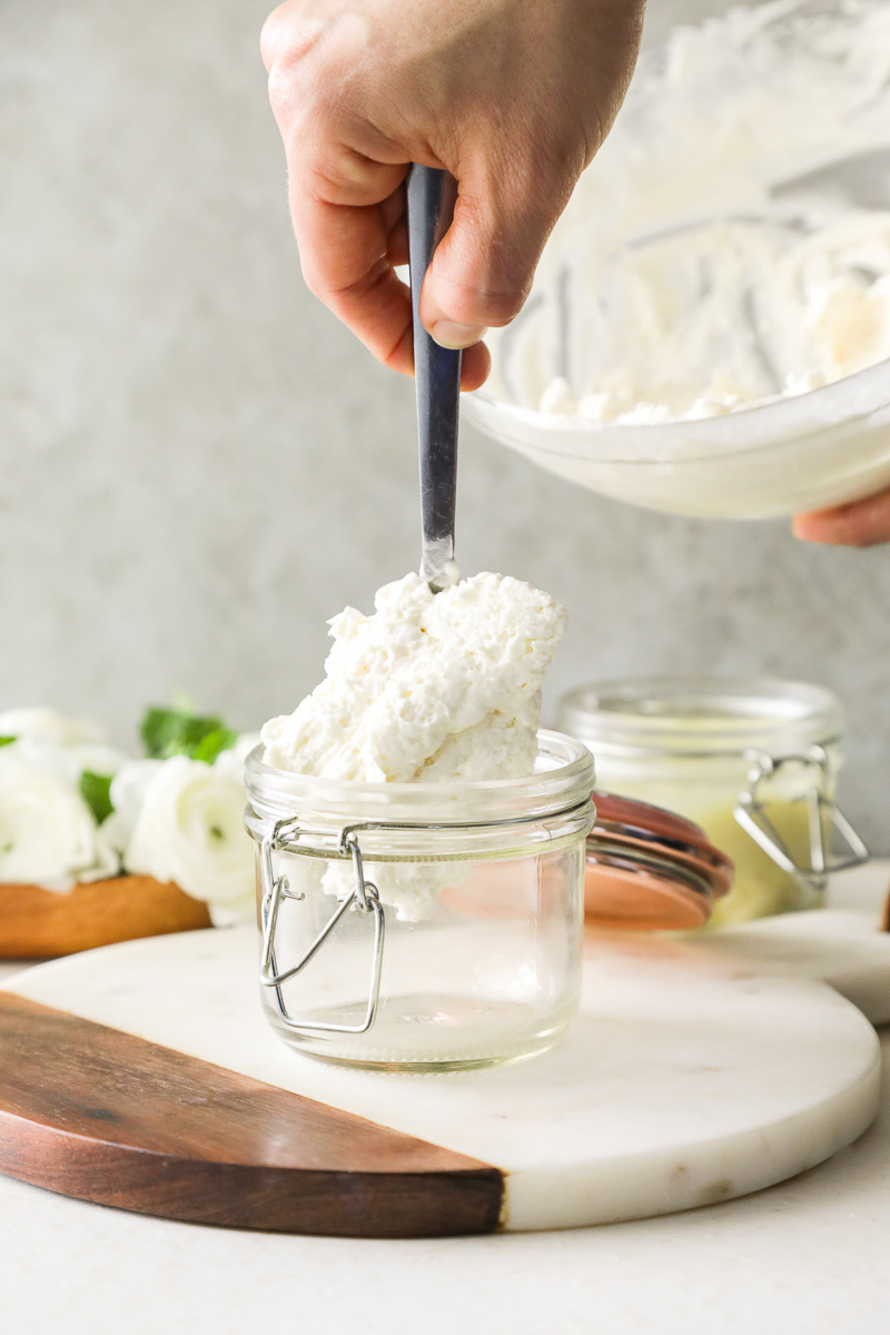 Spooning whipped body butter into a jar