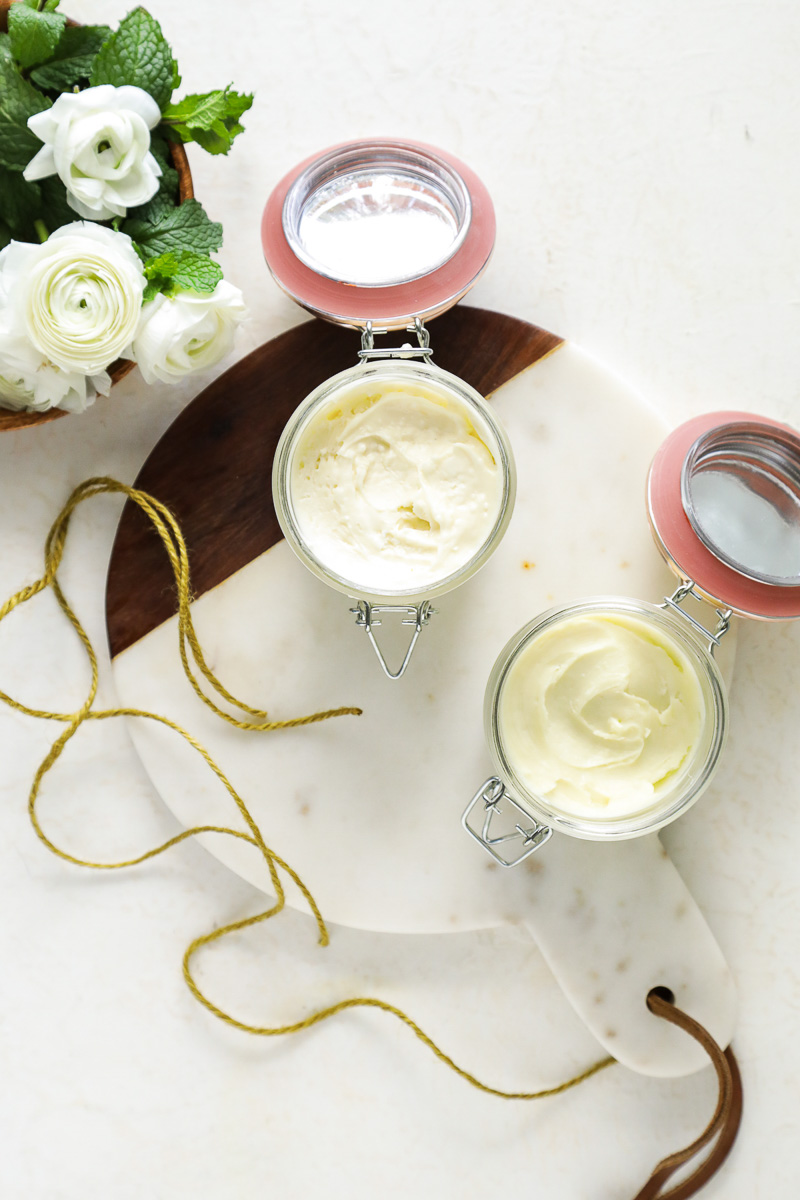 Two glass jars of body butter on a marble board.