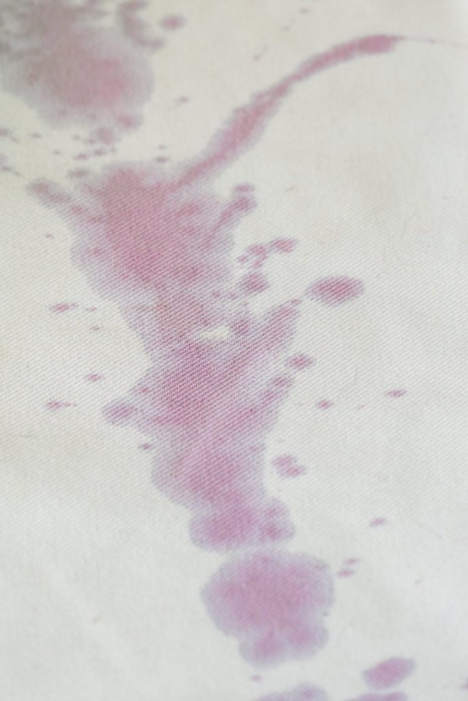 Red wine spilled on a white couch cover. 